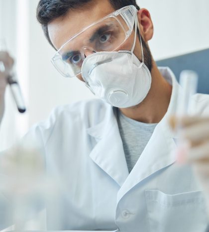 Portrait of a virologist holding a pair of test tubes with reagents in his hands